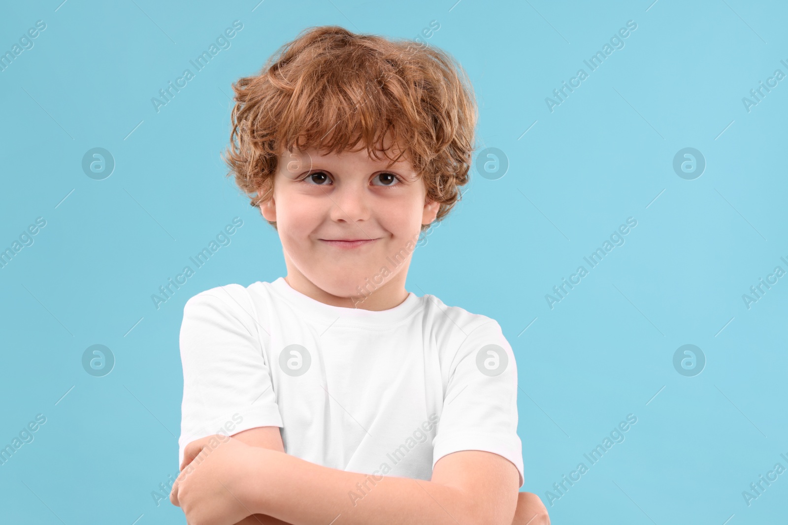 Photo of Portrait of cute little boy on light blue background