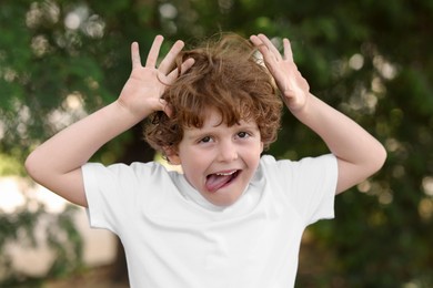 Photo of Portrait of emotional boy showing tongue outdoors. Cute child
