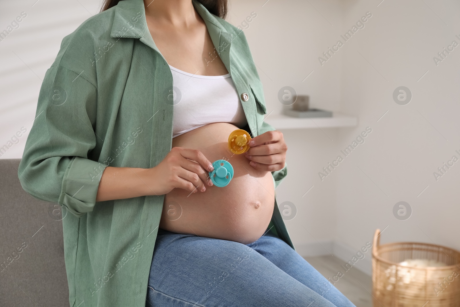 Photo of Pregnant woman with pacifiers at home, closeup. Expecting twins