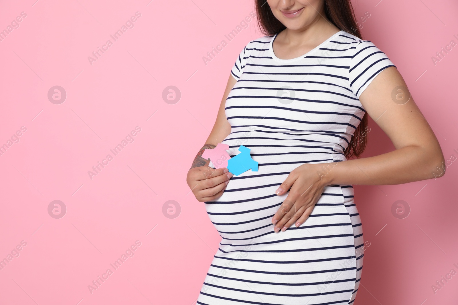 Photo of Pregnant woman with paper hearts on pink background, closeup and space for text. Expecting twins