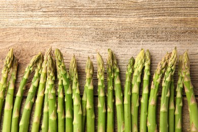 Photo of Fresh green asparagus stems on wooden table, flat lay. Space for text