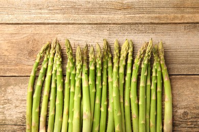 Fresh green asparagus stems on wooden table, flat lay