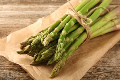 Photo of Bunch of fresh green asparagus stems on wooden table, closeup