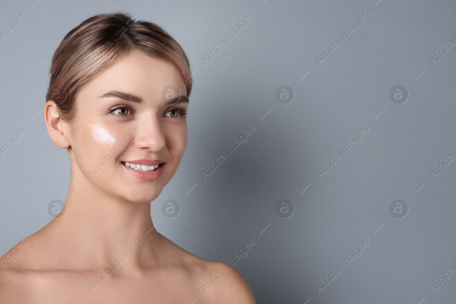 Photo of Beautiful woman with cream on her face against gray background, space for text