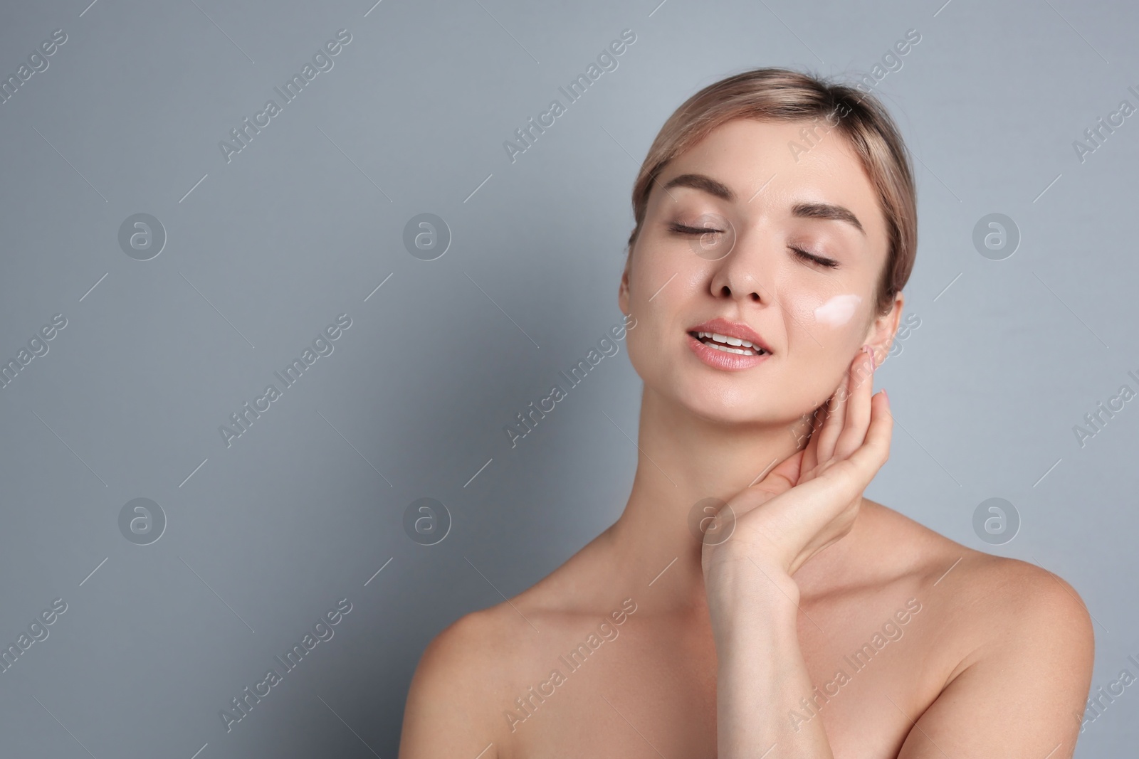 Photo of Beautiful woman with cream on her face against gray background, space for text