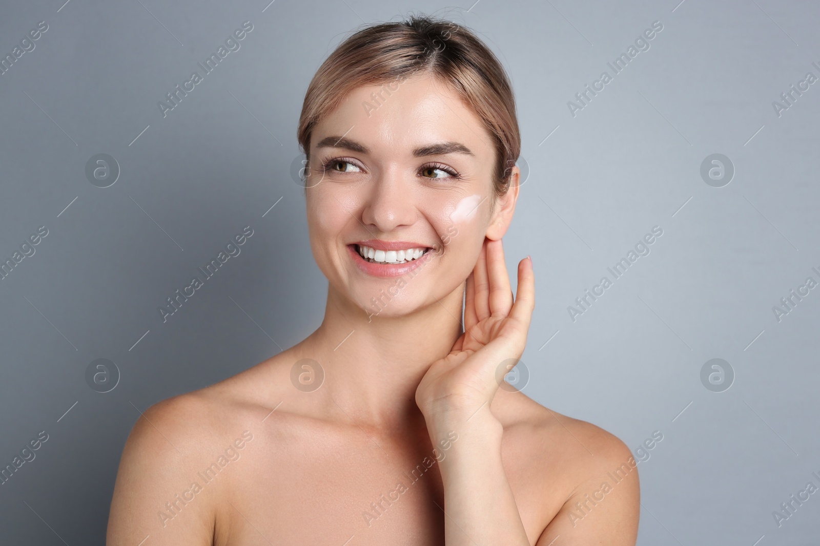 Photo of Beautiful woman with cream on her face against gray background