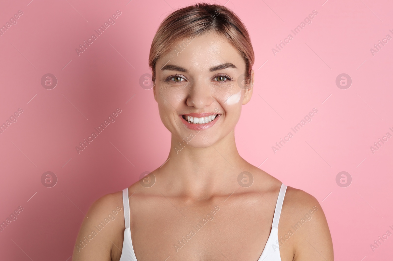 Photo of Beautiful woman with cream on her face against pink background