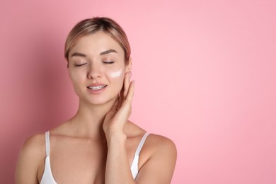 Photo of Beautiful woman with cream on her face against pink background, space for text
