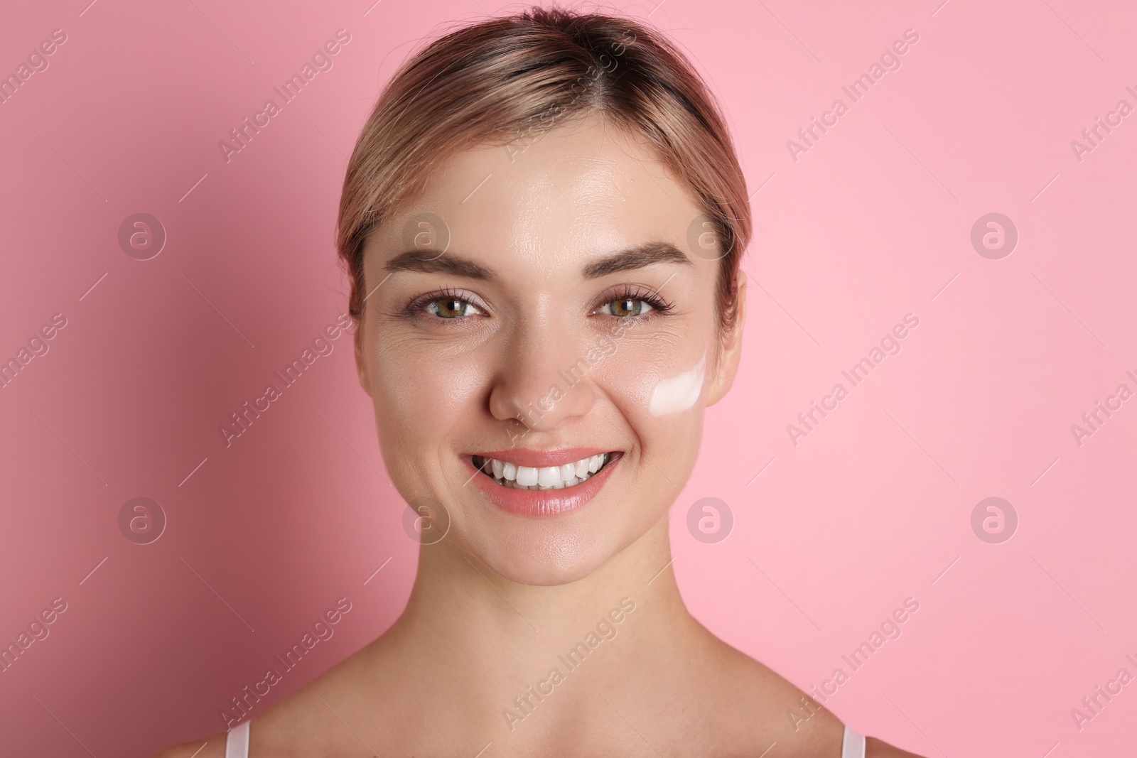 Photo of Beautiful woman with cream on her face against pink background