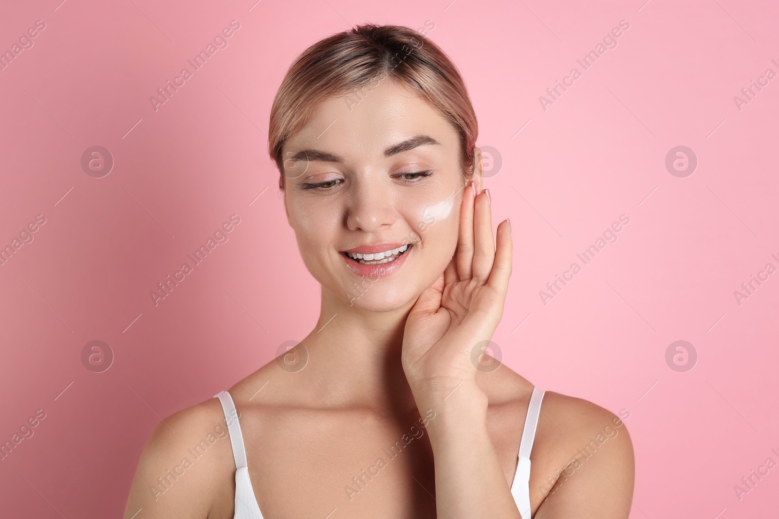 Photo of Beautiful woman with cream on her face against pink background