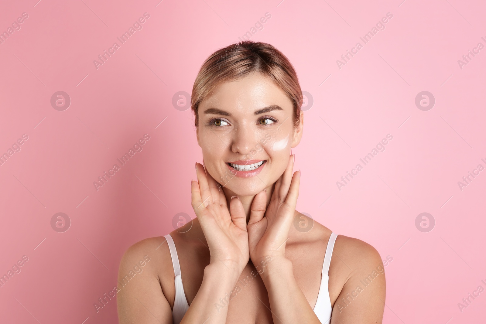 Photo of Beautiful woman with cream on her face against pink background