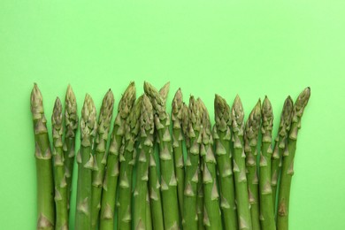 Fresh asparagus stems on green table, top view. Space for text