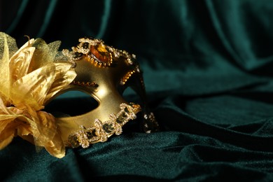 Beautiful golden carnival mask on green fabric, closeup