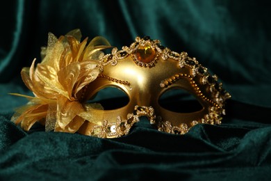 Beautiful golden carnival mask on green fabric, closeup