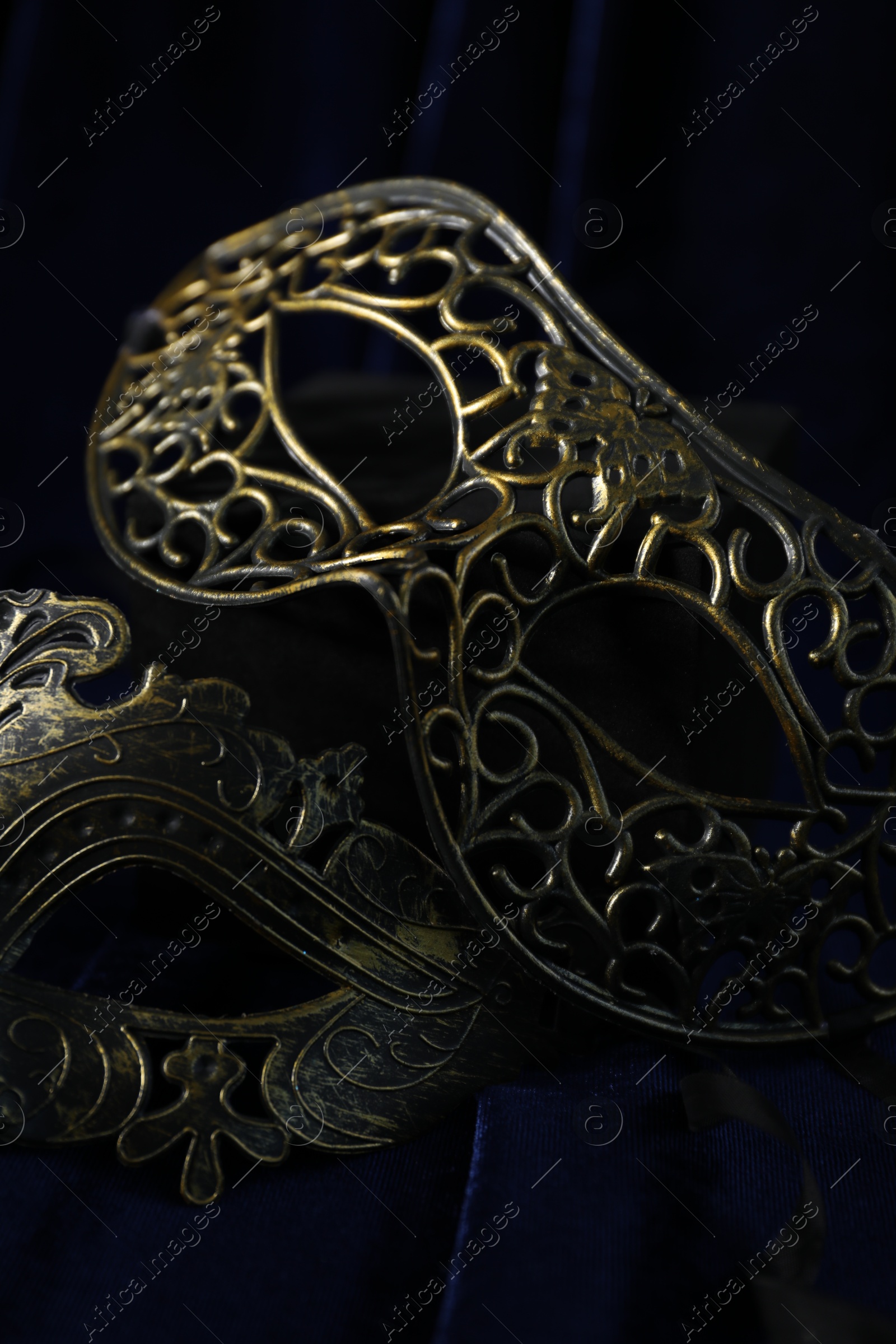 Photo of Beautiful carnival masks on blue fabric, closeup