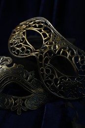 Photo of Beautiful carnival masks on blue fabric, closeup