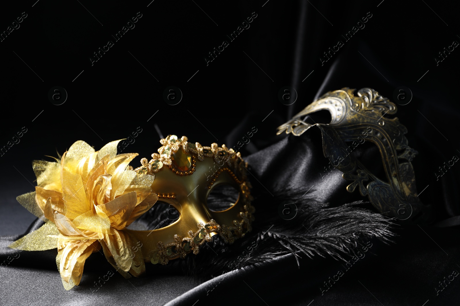 Photo of Beautiful golden carnival masks on black background, closeup