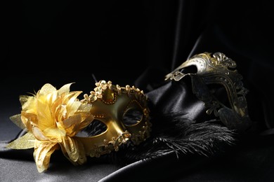 Photo of Beautiful golden carnival masks on black background, closeup