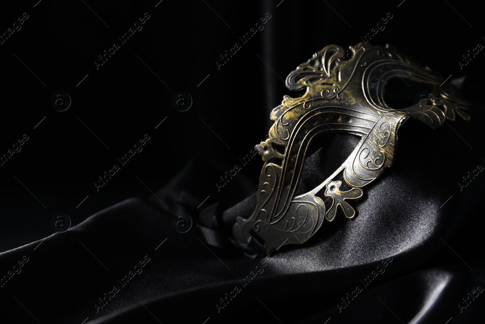 Photo of Beautiful golden carnival mask on black background, closeup. Space for text