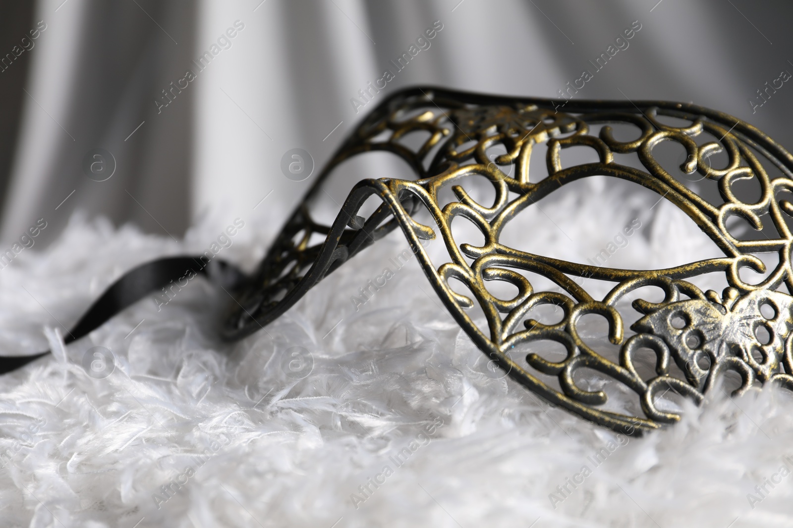 Photo of Beautiful carnival mask on white fabric, closeup