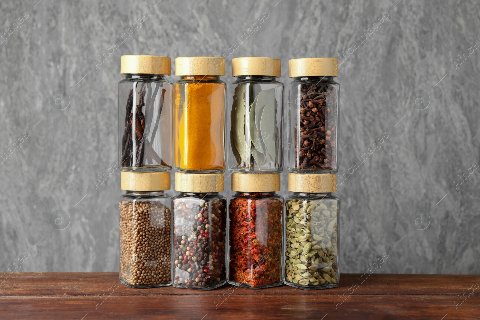 Photo of Different spices in glass jars on wooden table