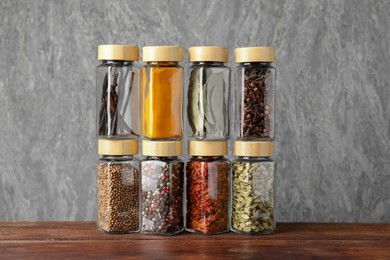 Different spices in glass jars on wooden table