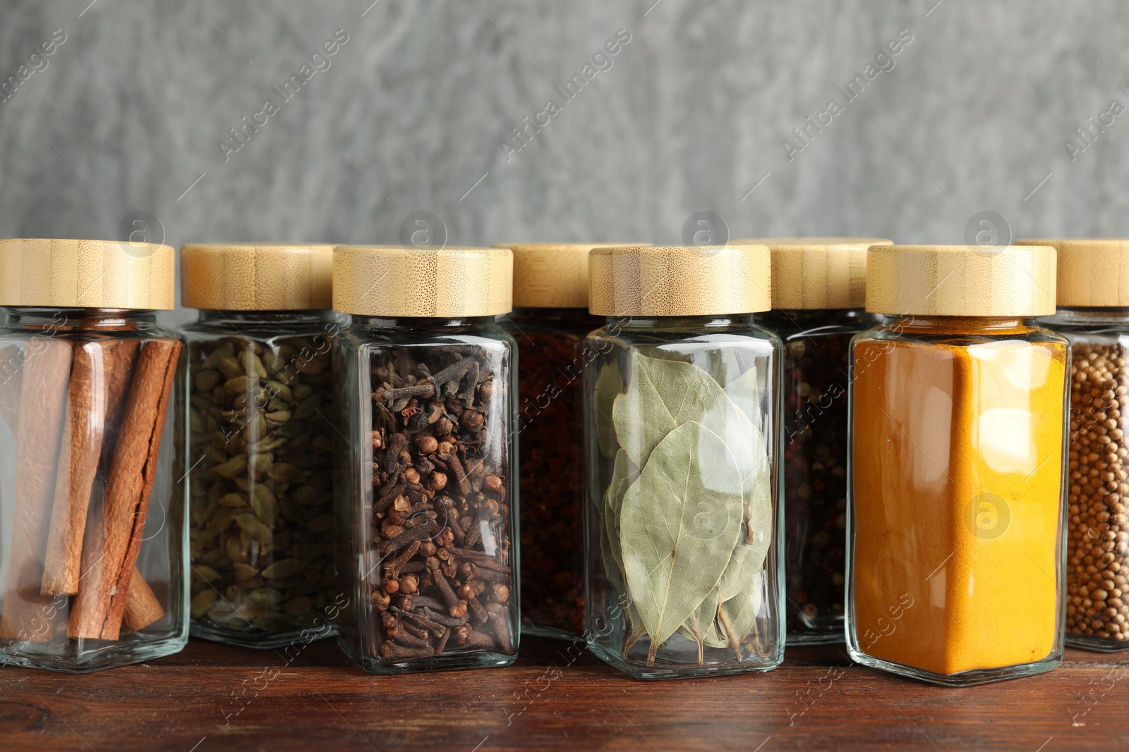 Photo of Different spices in glass jars on wooden table