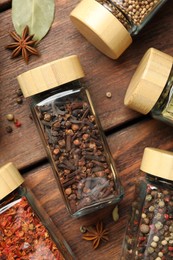 Photo of Different spices in glass jars on wooden table, flat lay