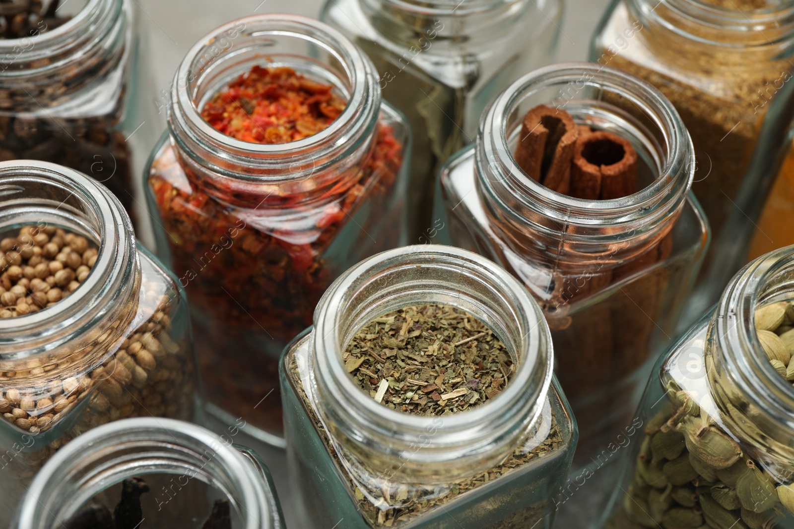 Photo of Different spices in glass jars on table, closeup