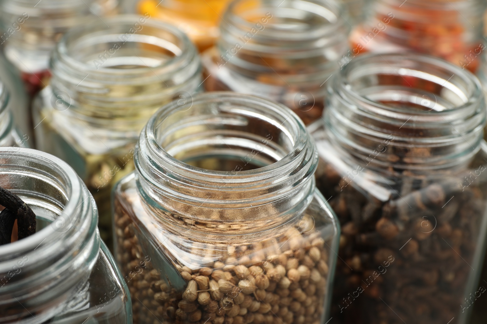 Photo of Different spices in glass jars on table, closeup