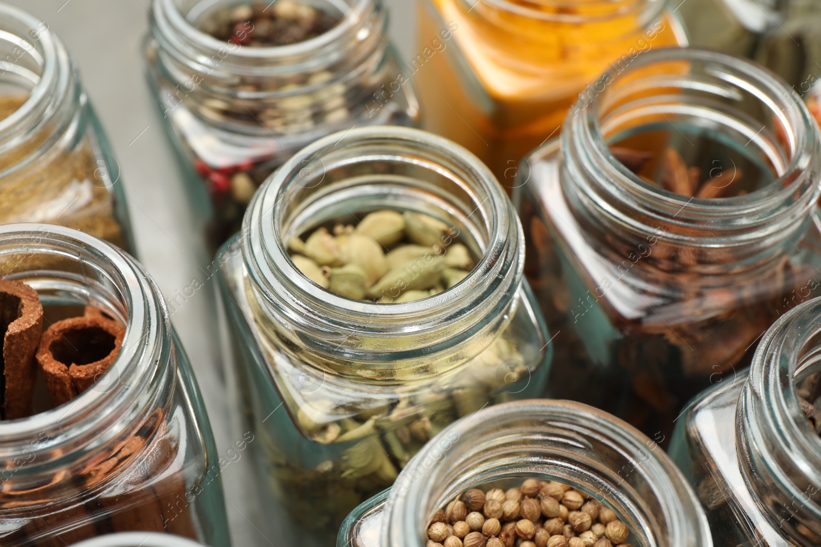 Photo of Different spices in glass jars on table, closeup