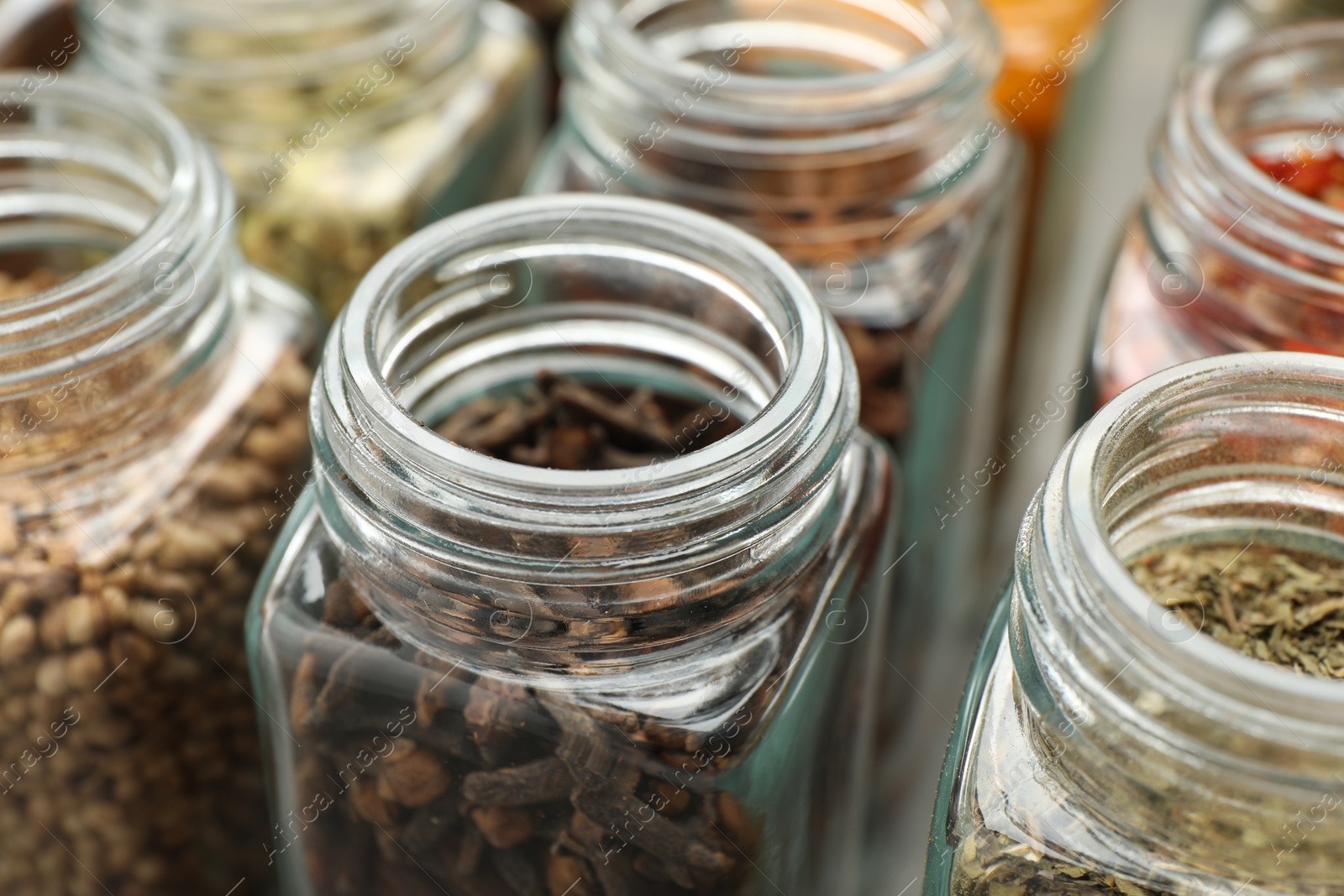 Photo of Different spices in glass jars on table, closeup