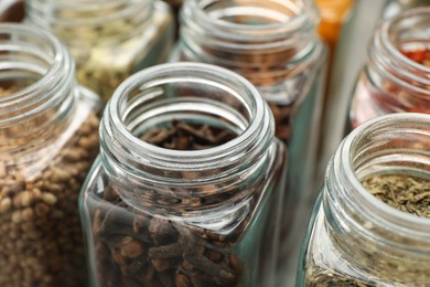 Different spices in glass jars on table, closeup