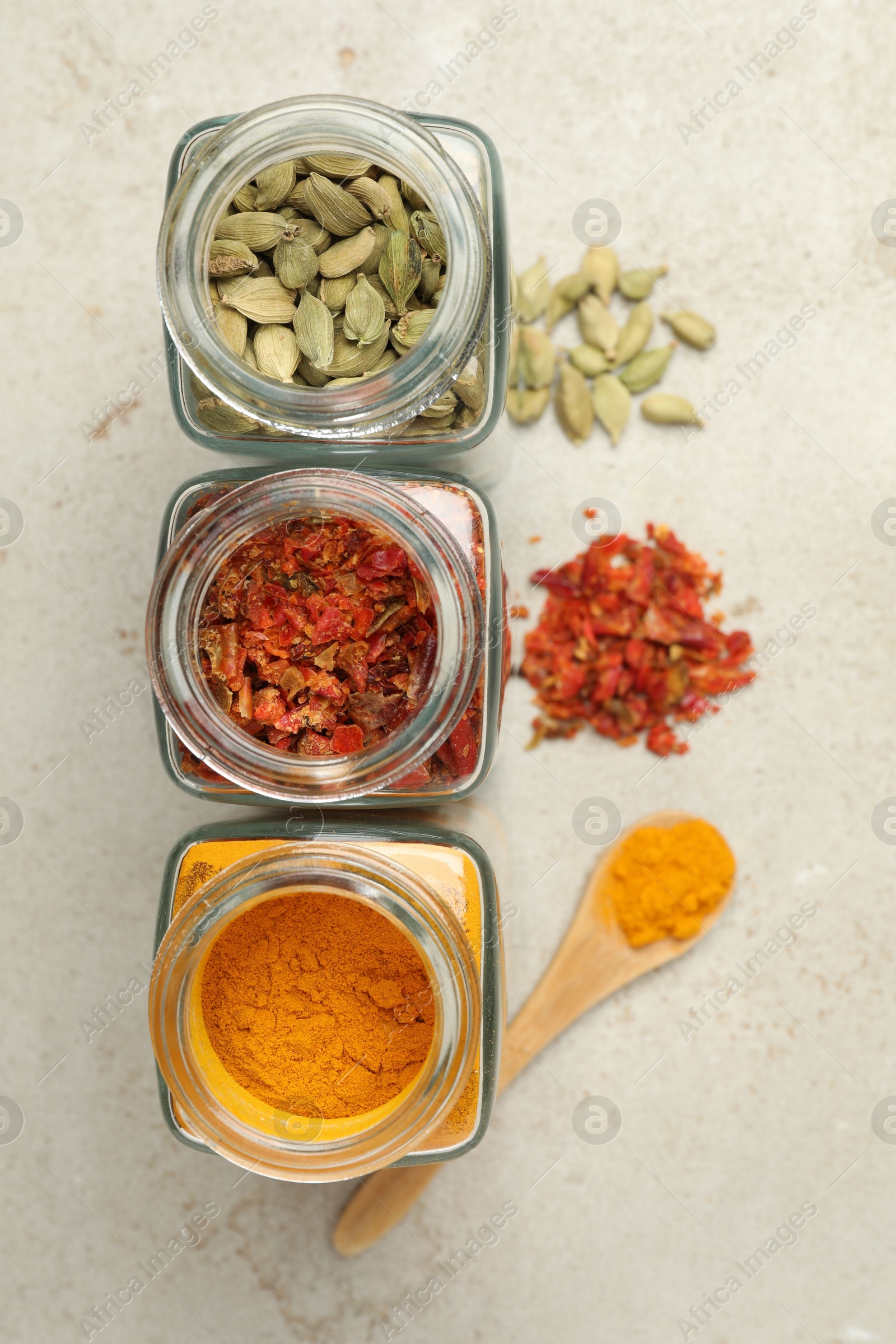 Photo of Different spices in glass jars on light grey table, flat lay