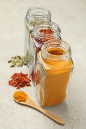 Different spices in glass jars on light grey table