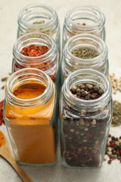 Different spices in glass jars on light grey table