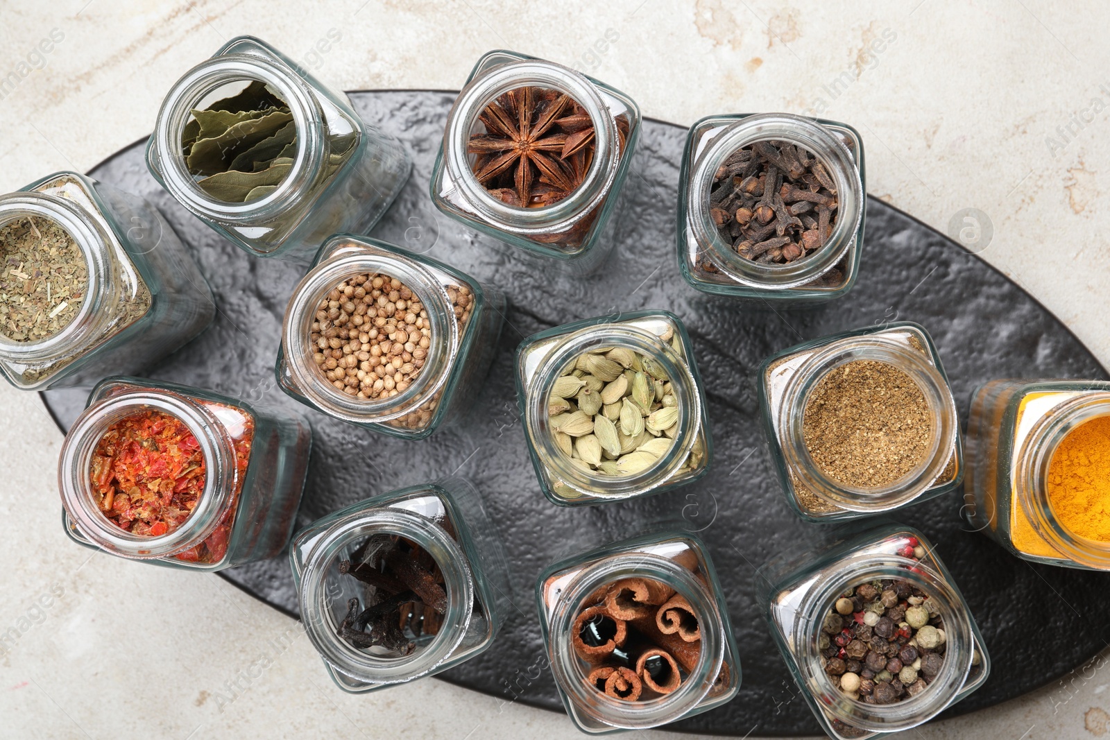 Photo of Different spices in glass jars on light grey table, top view