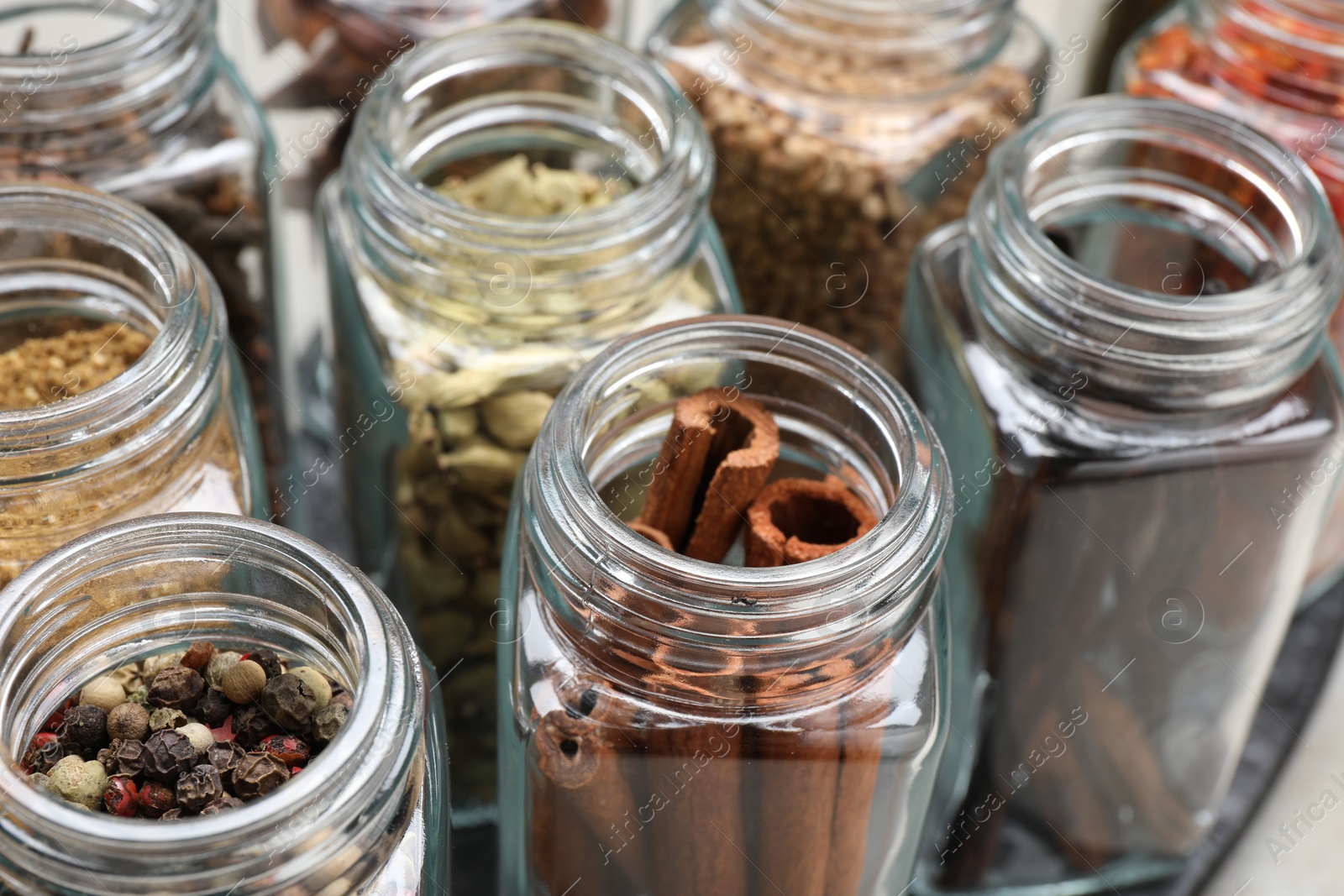 Photo of Different spices in glass jars on table, closeup