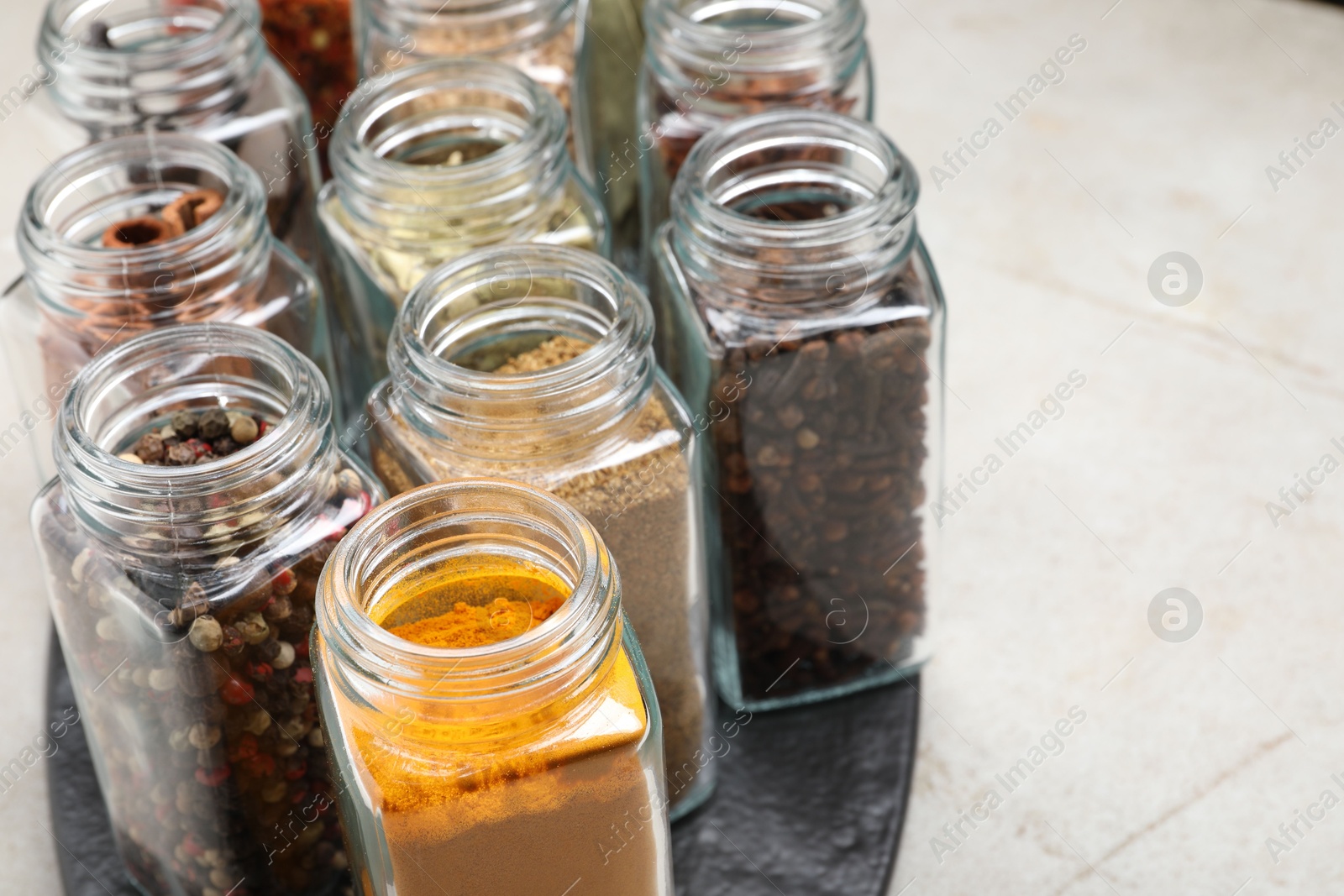 Photo of Different spices in glass jars on light grey table