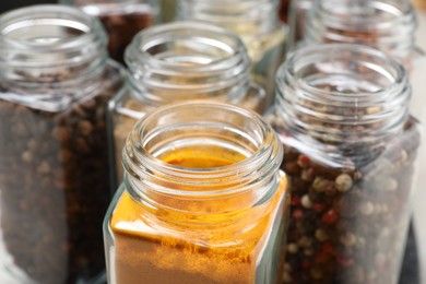 Photo of Different spices in glass jars on table, closeup