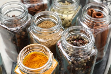 Different spices in glass jars on table, closeup