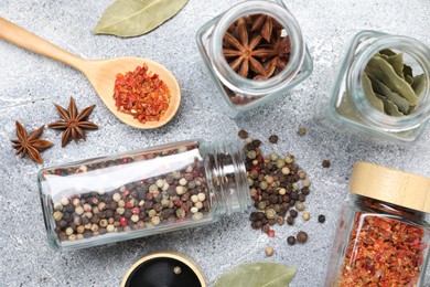 Different spices in glass jars on grey table, flat lay