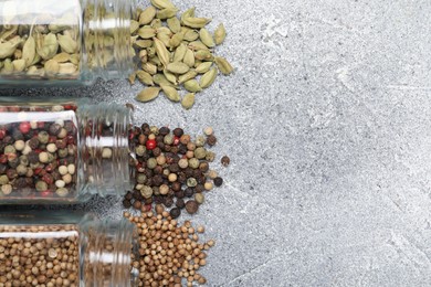 Photo of Different spices in glass jars on grey table, top view. Space for text