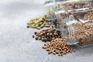 Photo of Different spices in glass jars on grey table, closeup. Space for text