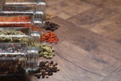 Different spices in glass jars on wooden table, space for text