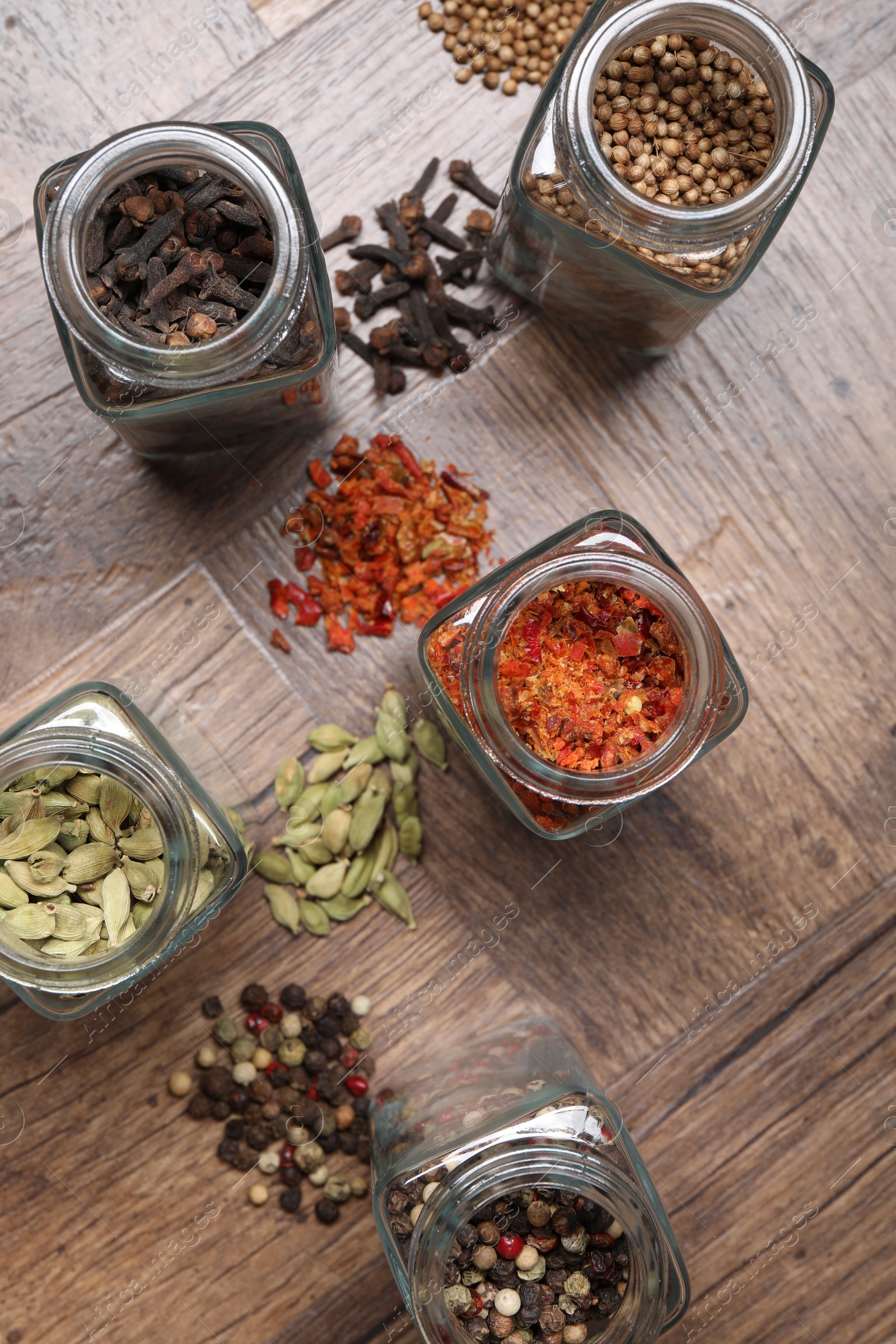 Photo of Different spices in glass jars on wooden table, flat lay