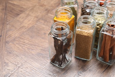 Photo of Different spices in glass jars on wooden table, space for text