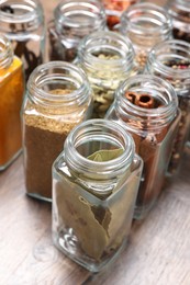 Different spices in glass jars on wooden table