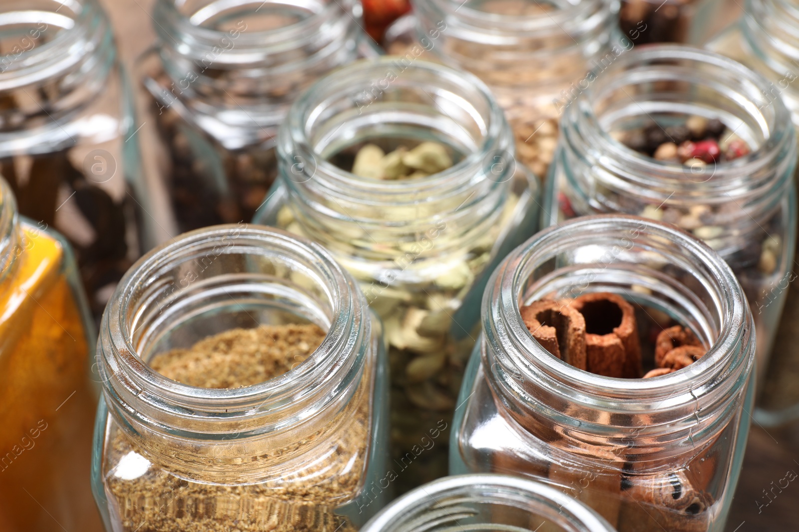 Photo of Different spices in glass jars on table, closeup