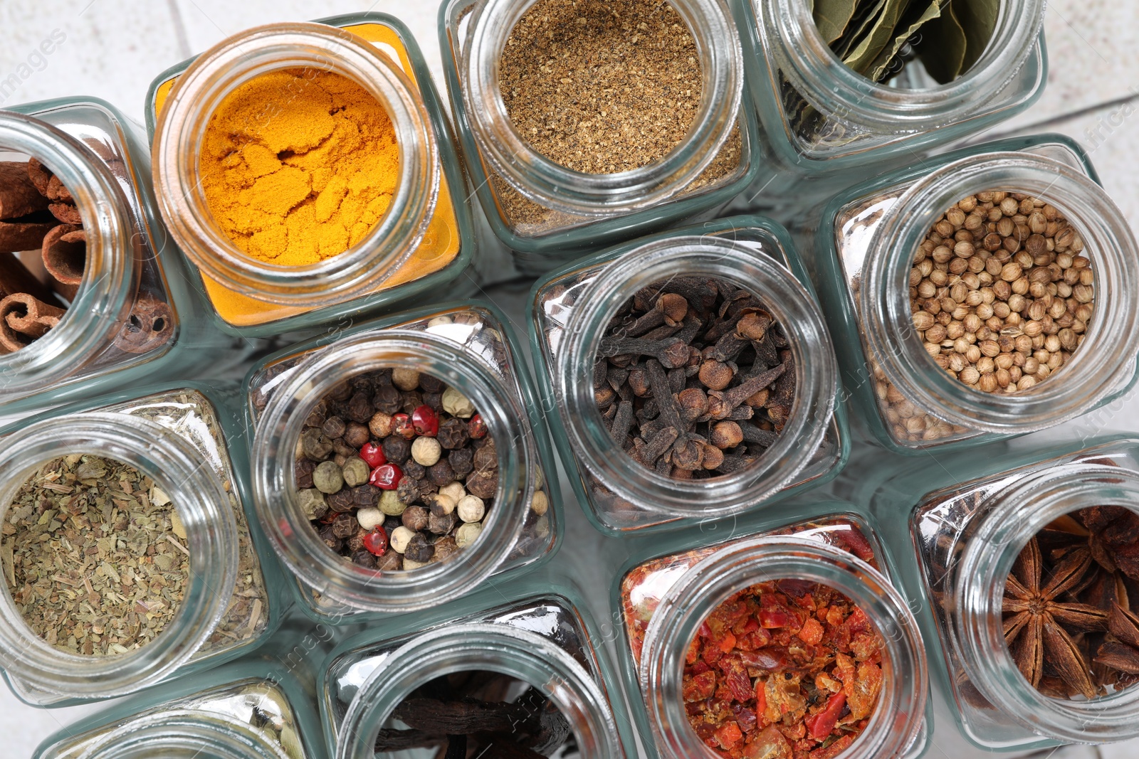 Photo of Different spices in glass jars on table, top view